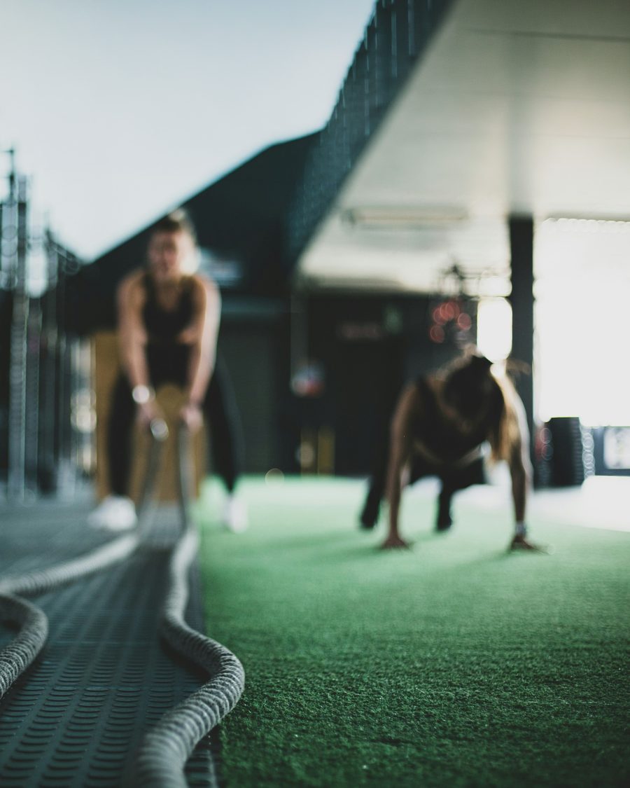 Athletes doing battle ropes and push-ups on turf